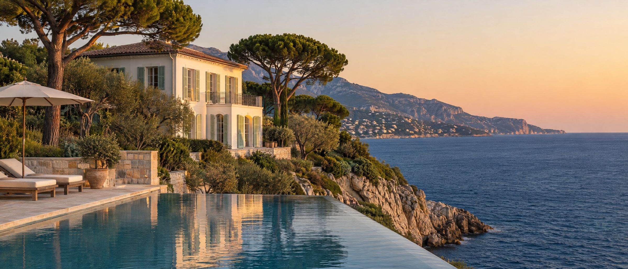 A white villa above an infinity pool on a rocky point near Roquebrune-Cap-Martin, the hour before sunset
